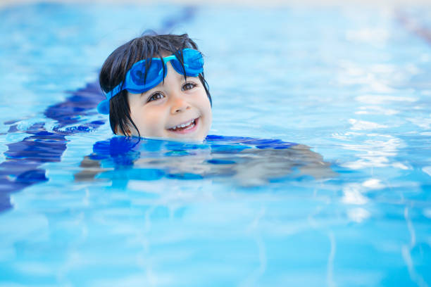 ragazzo felice che si gode l'estate in piscina - splashing color image front view head and shoulders foto e immagini stock