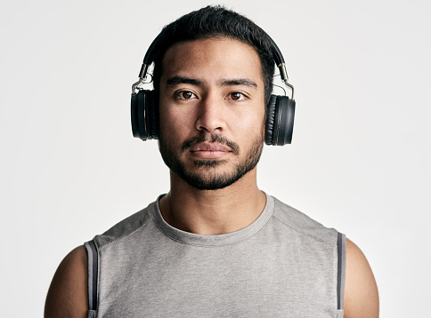 Studio portrait of a sporty young man wearing headphones against a white background