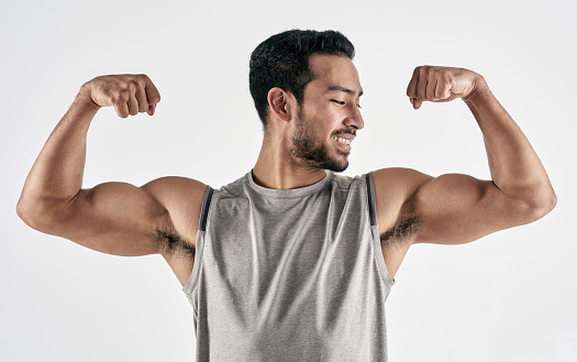 Studio shot of a muscular young man flexing his biceps against a white background