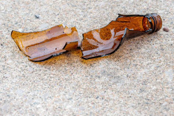 bottiglia di birra rotta sdraiata su un marciapiede - close up of a broken bottle, street foto e immagini stock