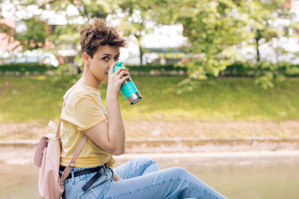 istock Young woman relaxing by the river and drinking coffee 1303391962