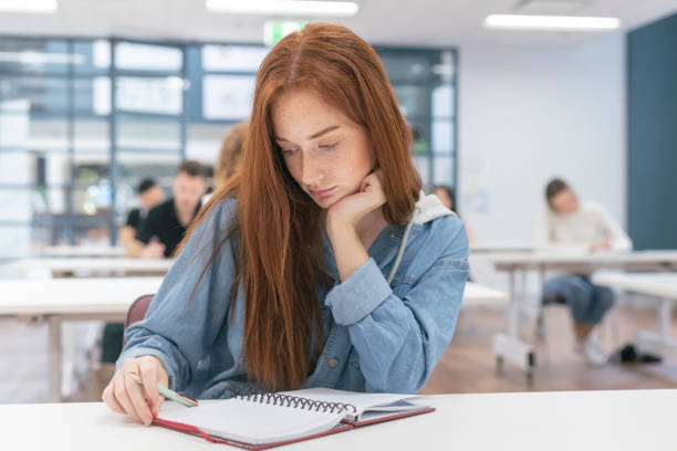 istock A gorgeous millennial woman writes in a notebook while attending univeisity class 1303392247