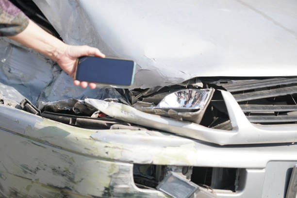 istock hand take photo of crashed damaged broken car. automobile crash accident 1303392520