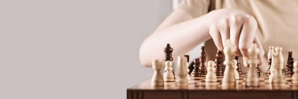 얼굴없는 소년과 배너는 게임 전략을 개발합니다. 손은 체스 조각을 잡고 손에 이동, 선택적 초점을 만든다 - chess leisure games chess queen skill 뉴스 사진 이미지