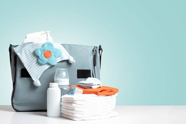 Diaper bag on blue background. Copy space. Bag packed for trip or journey or for walking with baby. Diapers, bottle and other necessary things for baby and mom. Diaper bag to maternity hospital. Copy space. Blue background. baby goods stock pictures, royalty-free photos & images