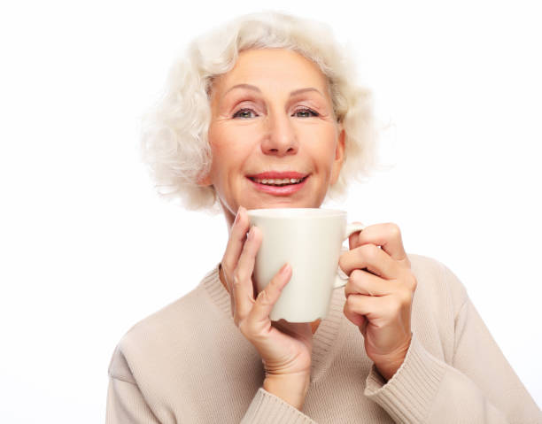 istock old excited lady smiling laughing, holding cup drinking coffee or tea 1303394853