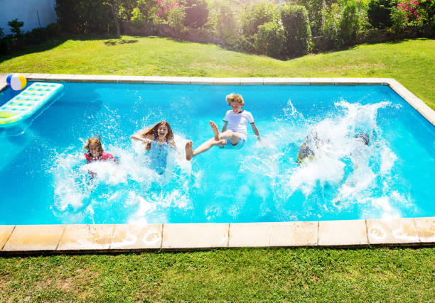 istock Happy kids fall and splash into the pool water 1303401917