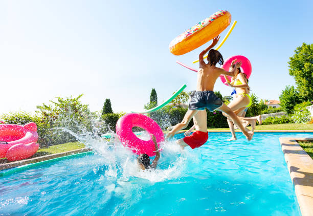 éclaboussures d’enfants dans la piscine avec des jouets gonflables - swimming pool child swimming buoy photos et images de collection