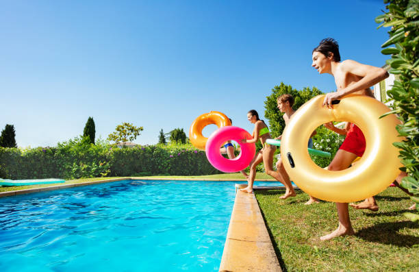 istock Kids with inflatable buoys run dive into the pool 1303401925