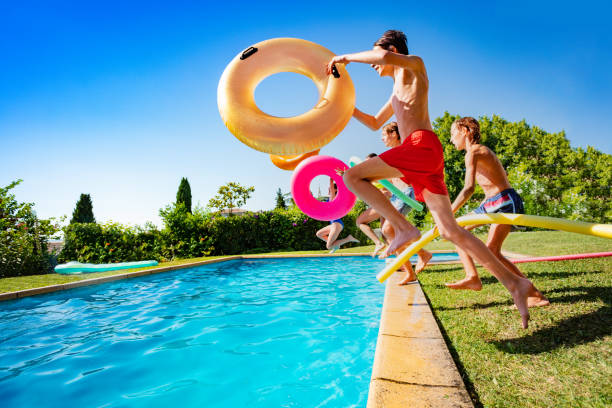 istock Kids with inflatable buoys jump dive into pool 1303401926