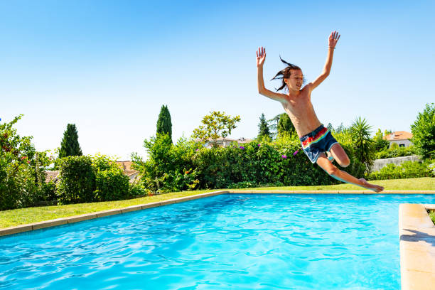 istock Boy jump in mid air into swimming pool screaming 1303401929