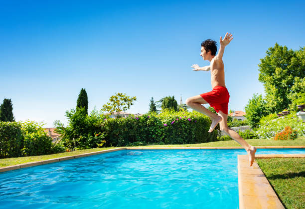 istock Handsome boy jump in mid air into water pool 1303401942