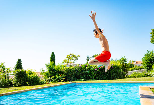 istock Happy boy jump in mid air pose inside the pool 1303401945