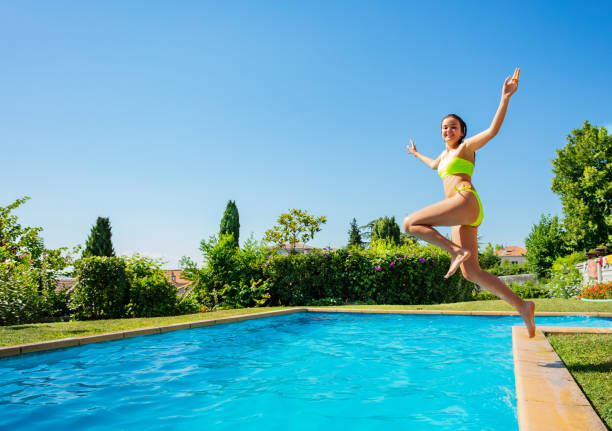 istock Happy girl jump in mid air pose inside the pool 1303401947
