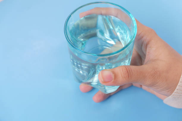 istock hand holding plastic glass of blue background 1303405315