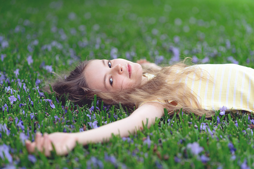 Young girl relaxing on the grass with Jacaranda tree flowers