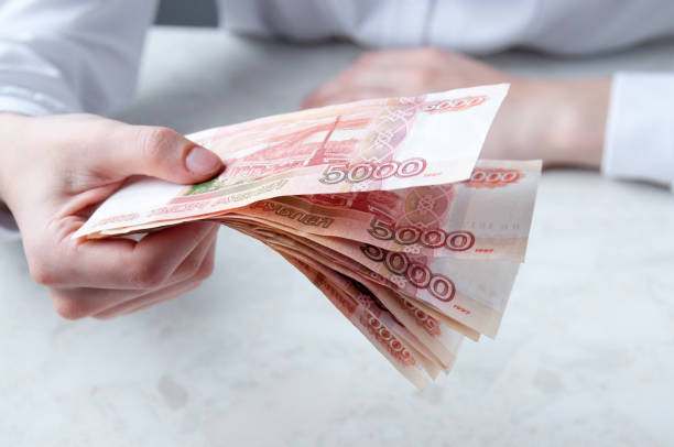 istock A woman's hand is holding a bundle of large five thousand rubles bills over the table 1303407470