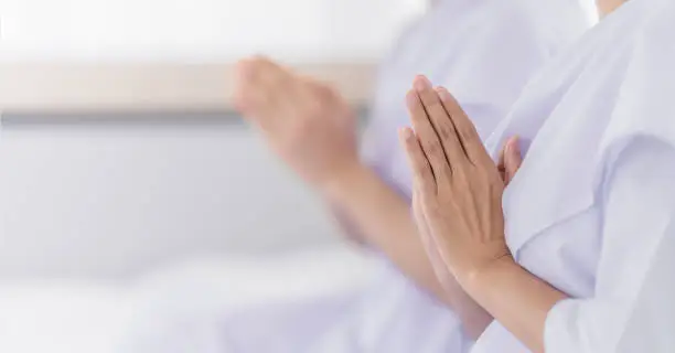 hands of religious Asian buddhist people in white cloth praying and chanting