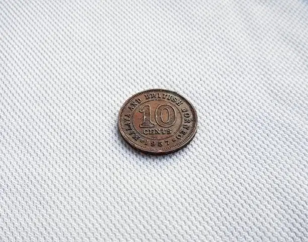 Photo of a 10 cents coin found in india. malaya and british borneo 1957 year. 64 year old coin tells the history of british and india.