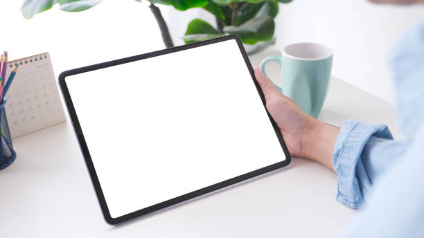 istock Close up of man hand holding digital tablet with blank screen on working table background for mock up, template 1303416992