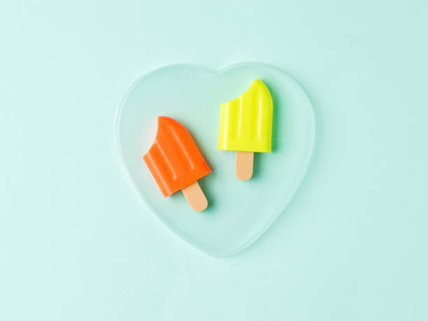Two bitten popsicles in a glass heart on a blue background.
