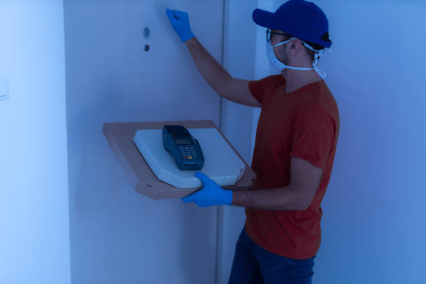 istock Delivery guy with protective mask holding pizza box at the door. 1303427155