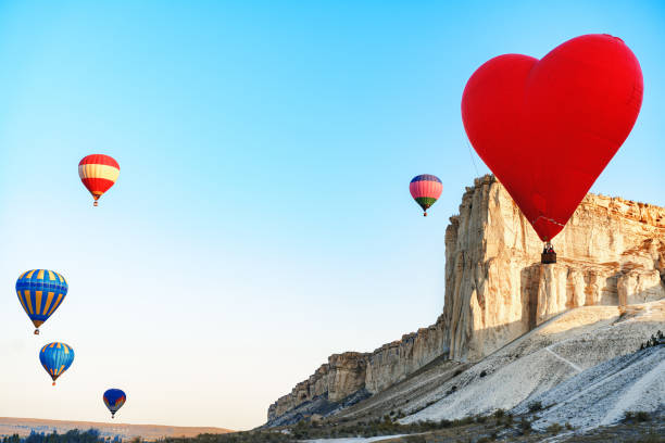 istock Red heart-shaped air balloon flying in the sky 1303428023