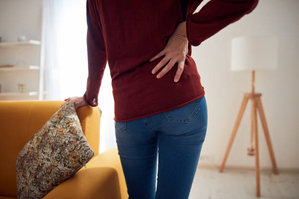 Woman with back / hip pain at home. Woman with back / hip pain at home. tetanospasmin stock pictures, royalty-free photos & images