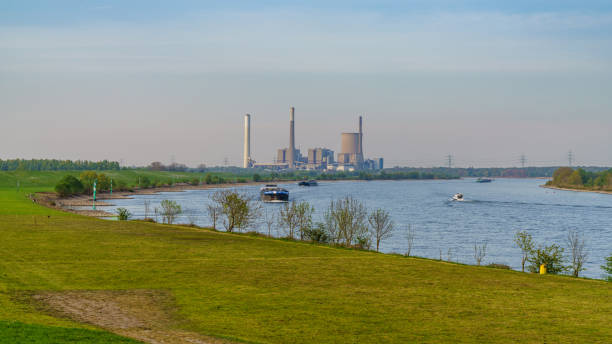 View towards the River Rhine in Orsoy, Germany Rheinberg, North Rhine-Westphalia, Germany - April 16, 2020: View at the River Rhine in Orsoy, with the Voerde power station in the background rheinberg illumination stock pictures, royalty-free photos & images