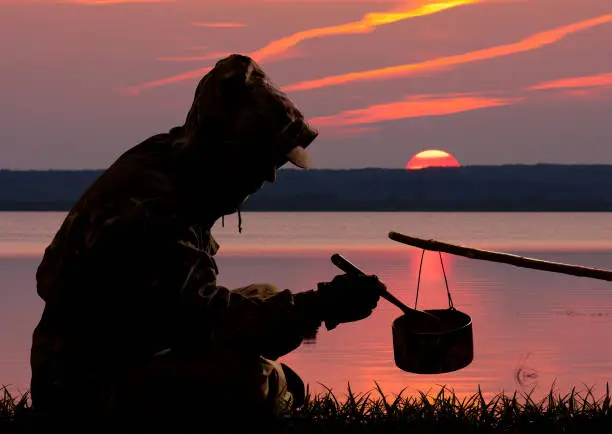 Photo of hunter eating out of the pot at sunset