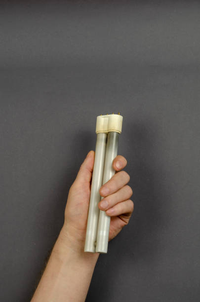 istock A hand holds a burnt-out  fluorescent lamp on a gray background. 1303437374