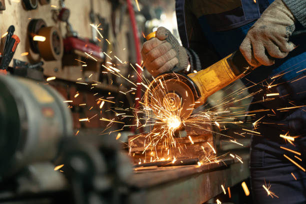 istock Locksmith in special clothes and goggles works in production. Metal processing with angle grinder. Sparks in metalworking 1303439441