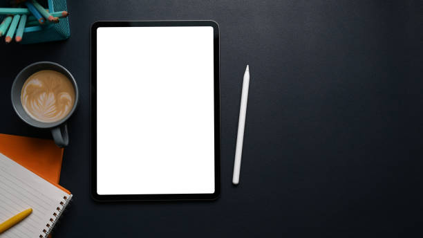 istock Mock up digital tablet with blank screen, coffee cup, stylus pen, notebook and copy space on black leather. 1303443193