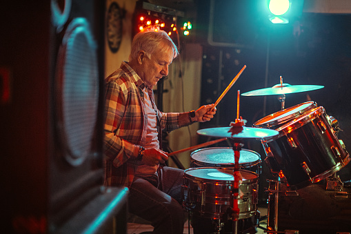 Senior man play drums in the night club