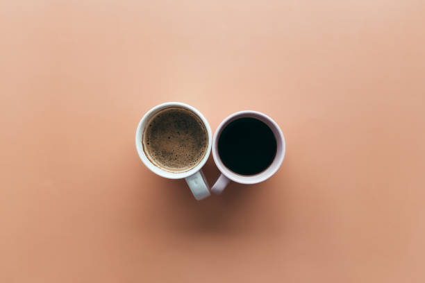 istock Two pink and blue coffee cups on beige background 1303443592