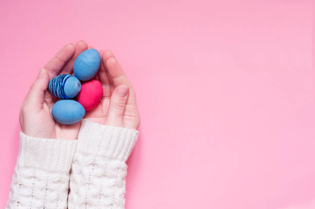 istock Colored Easter eggs in the palms of your hands on a pink background. Top view. 1303443804