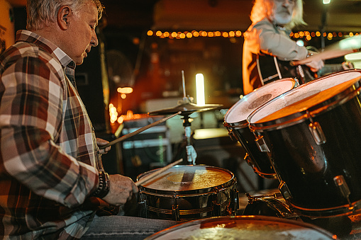 Senior mans playing music, guitar and drums in the club for friends