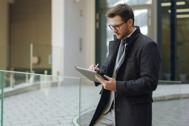 istock A handsome young executive working on his digital tablet outdoors 1303446273