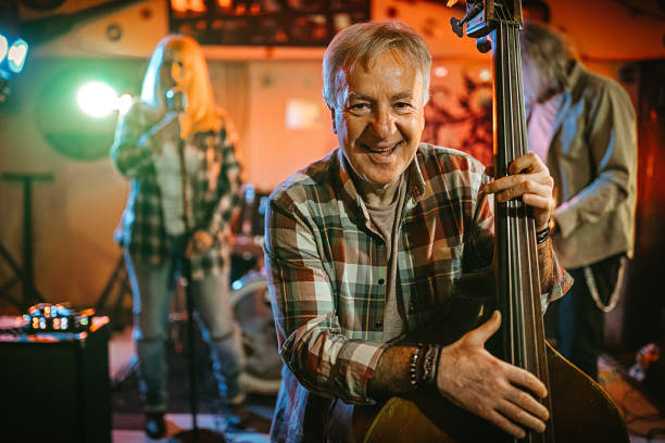 Frontman! Senior man play contrabass with his bend in the club for friends, make music, happy senior band string ensemble stock pictures, royalty-free photos & images
