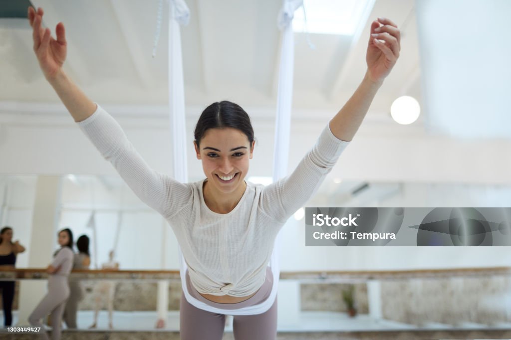 Aerial yoga Barre and yoga studio in Barcelona.
One smiling woman hinging from a flying yoga cloth. Aerial Yoga Stock Photo
