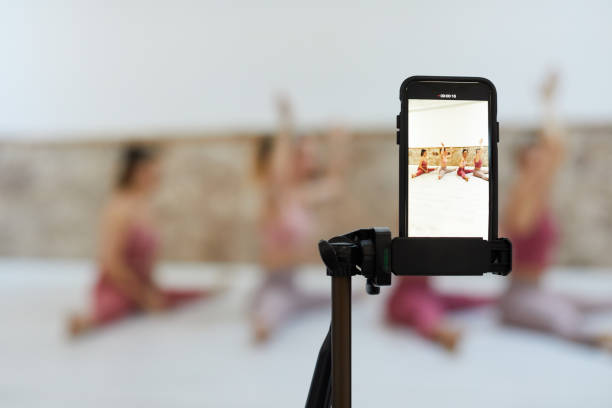 fermez-vous vers le haut de la vue d’un smartphone classant un cours de yoga. - tripod photos et images de collection