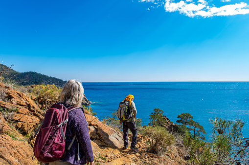 55-year-old woman 60-year-old man. Backpacking hiker.A path adjacent to the high sea. Sea view. A rocky region. The ancient Lycian way route has a unique Mediterranean view.