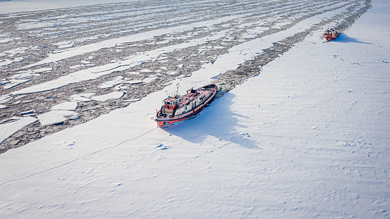 Two icebreakers on Vistula river crush the ice in winter, aerial view of Poland
