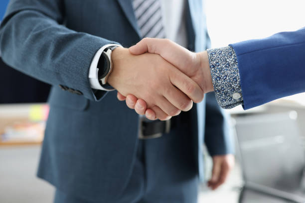 istock Two businessmen are shaking hands friendly closeup 1303455412