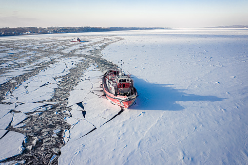 Icebreaker crushing ice on Vistula River in winter, aerial view of Poland