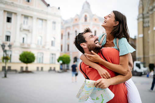 Happy couple on vacation having fun and sightseeing city with map