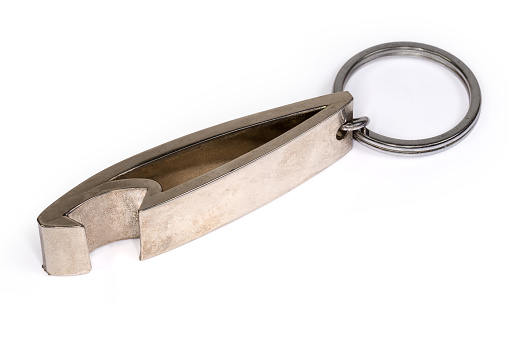 Metal bottle opener in the form of a keychain with attached steel split ring close-up on a white background