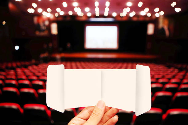 istock Hand holding cinema ticket at empty cinema 1303455905