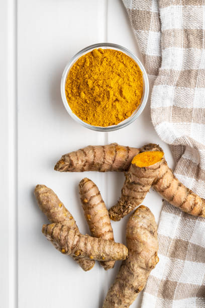 istock Indian turmeric powder and root. Turmeric spice. Ground turmeric 1303456078