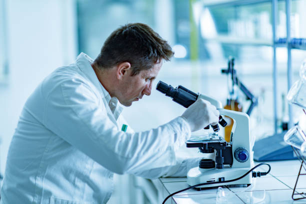 istock Mid adult male scientist working on a microscope. 1303459953